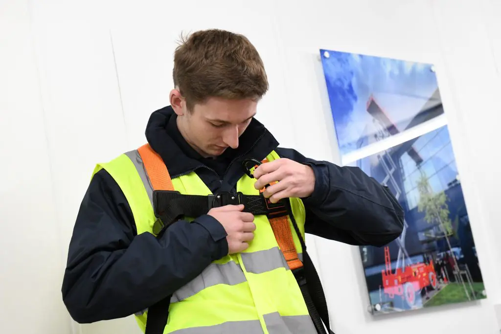 putting on a safety harness PPE Required for Using a MEWP - A Person Putting on a Safety Harness