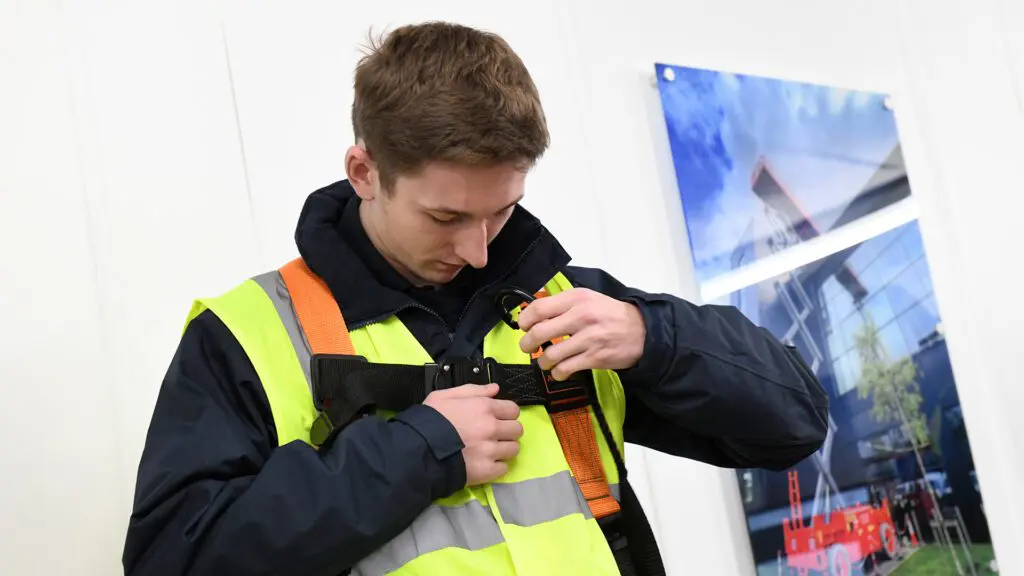 safety harness application an IPAF trainee wearing a harness before going to operate a boom lift